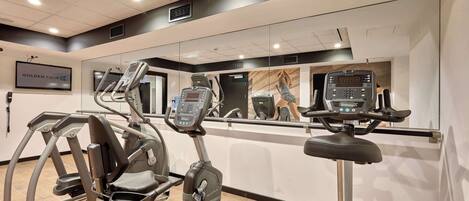 Un gimnasio con equipo de cardio, un espejo grande y un letrero que dice 'GOLDEN TULIP'.