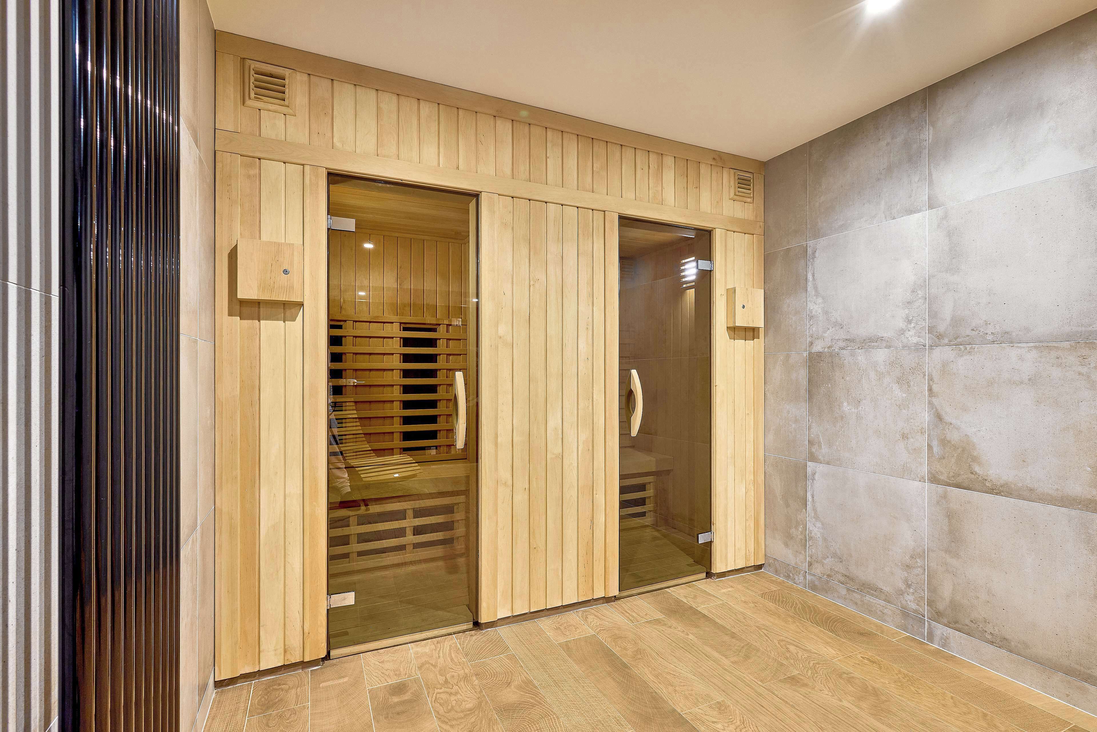 A modern interior with wooden paneling, a glass door leading to a sauna area, and a tiled wall.