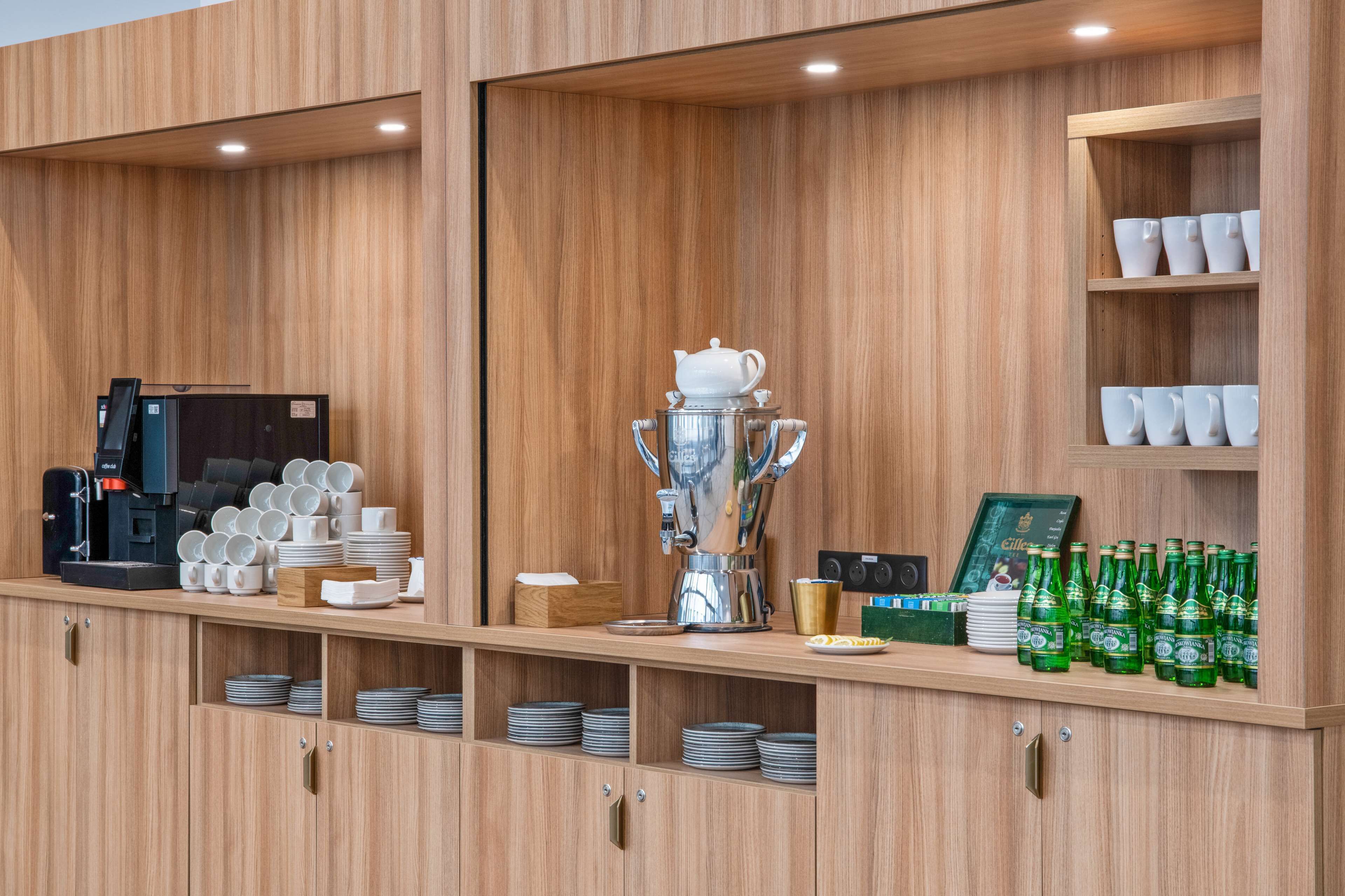 Un coin café équipé d’une machine à café, de tasses et d’une grande cafetière.