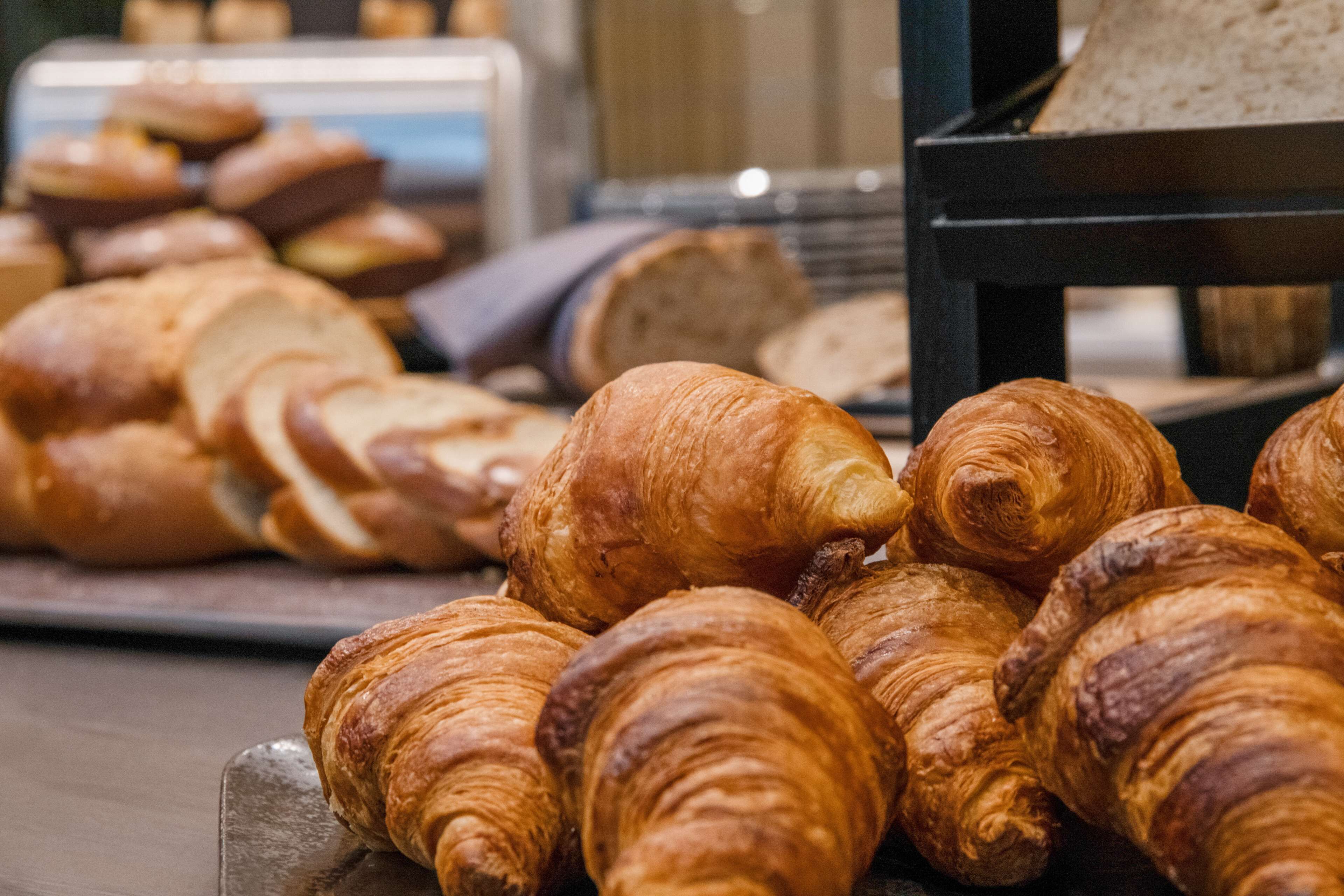 A variety of baked goods, including croissants and bread, displayed on a wooden board.