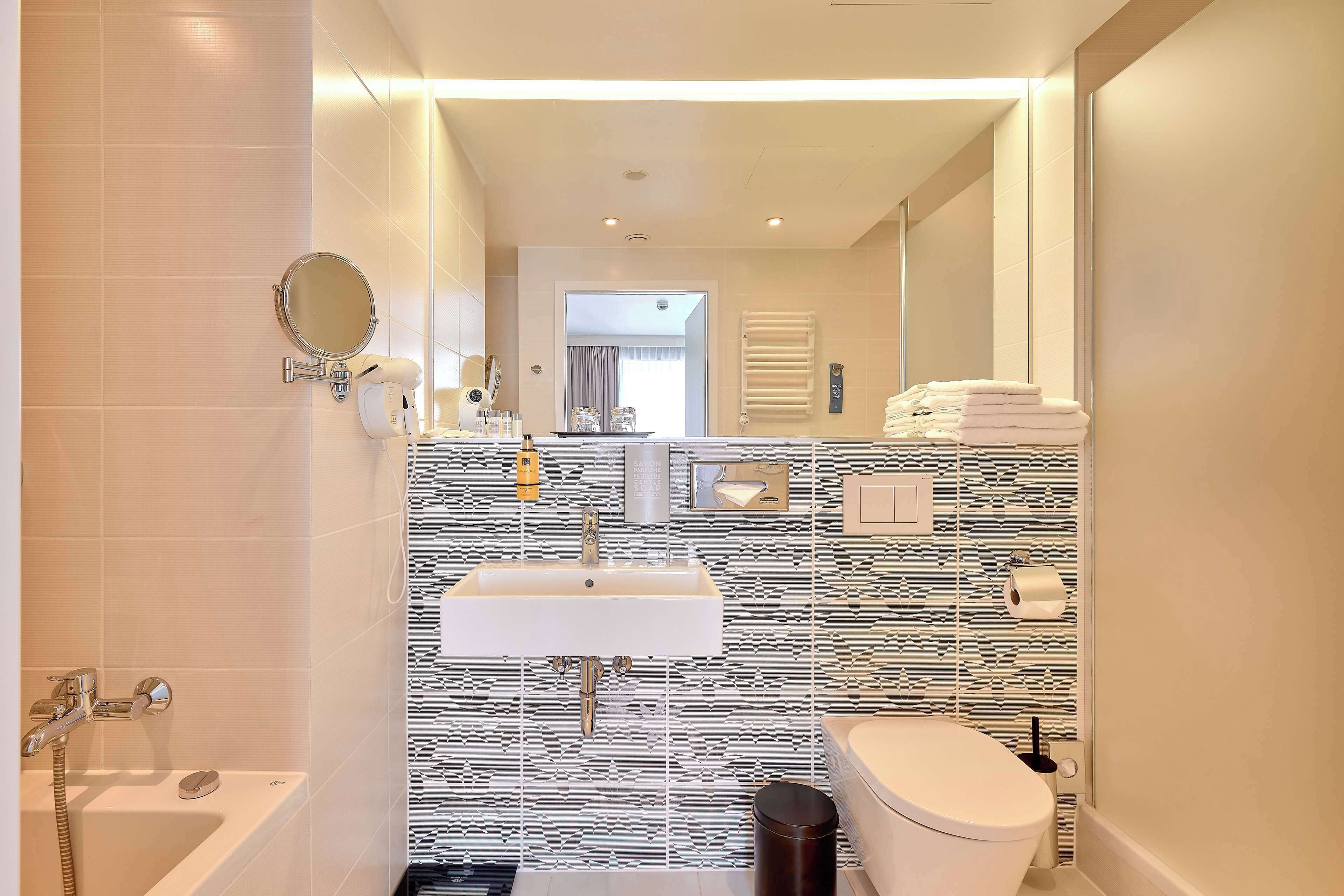 A modern bathroom with a white sink, a toilet, a bathtub, and a shower.