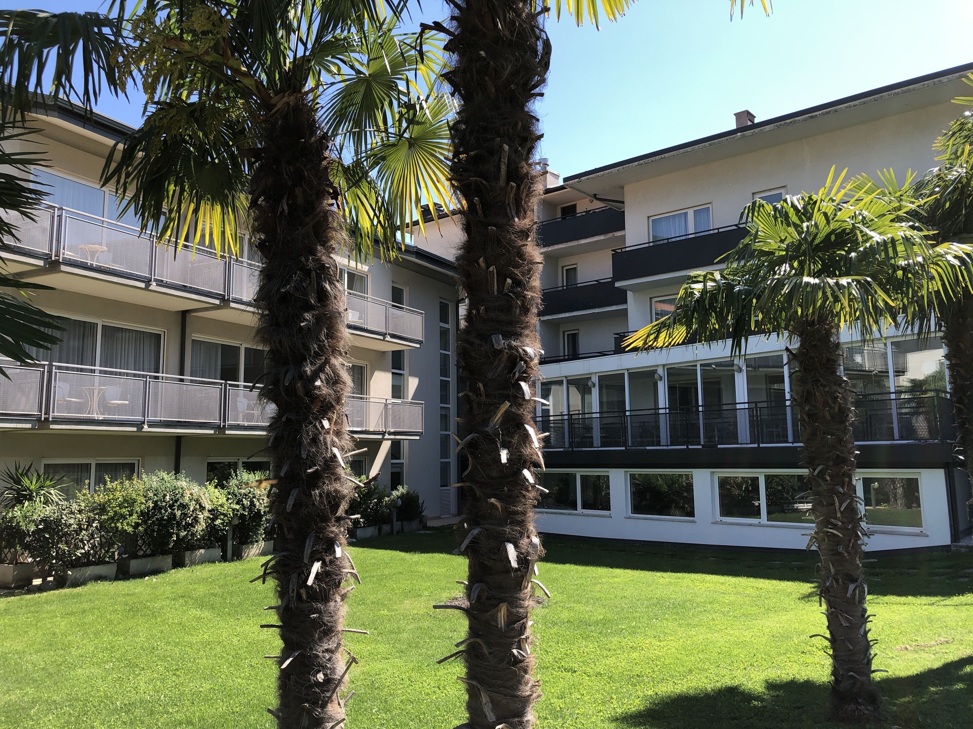 A multi-story hotel with balconies and a well-maintained lawn.