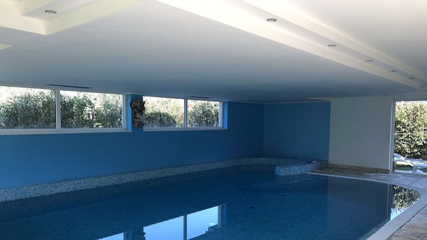Una amplia piscina interior con agua cristalina y paredes pintadas de azul claro.