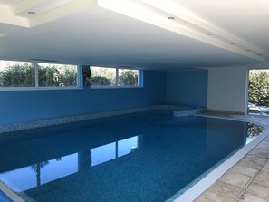A large indoor swimming pool with clear blue water, surrounded by walls painted in a light blue color. - Hotel Piccolo Mondo (Nago-Torbole)