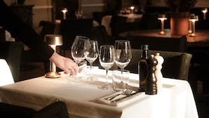 A table set for dining with wine glasses, a bottle, and salt and pepper shakers.