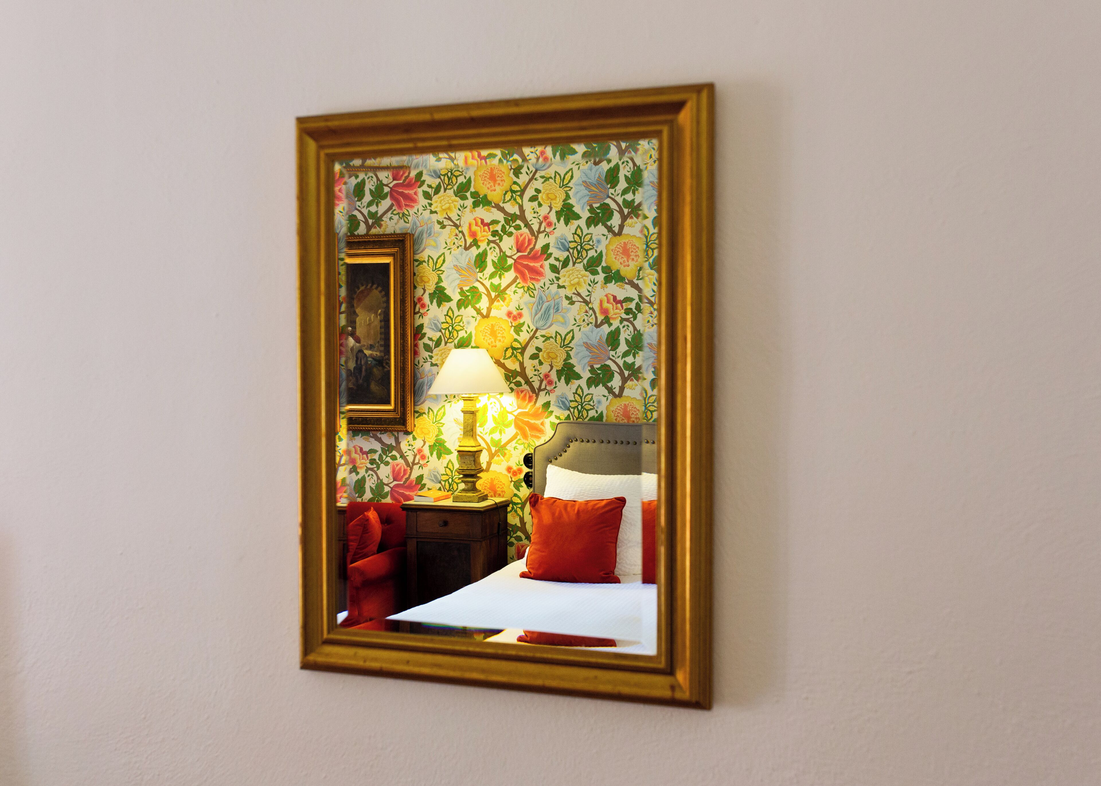 A room with a bed, a nightstand, a lamp, and a painting on the wall.