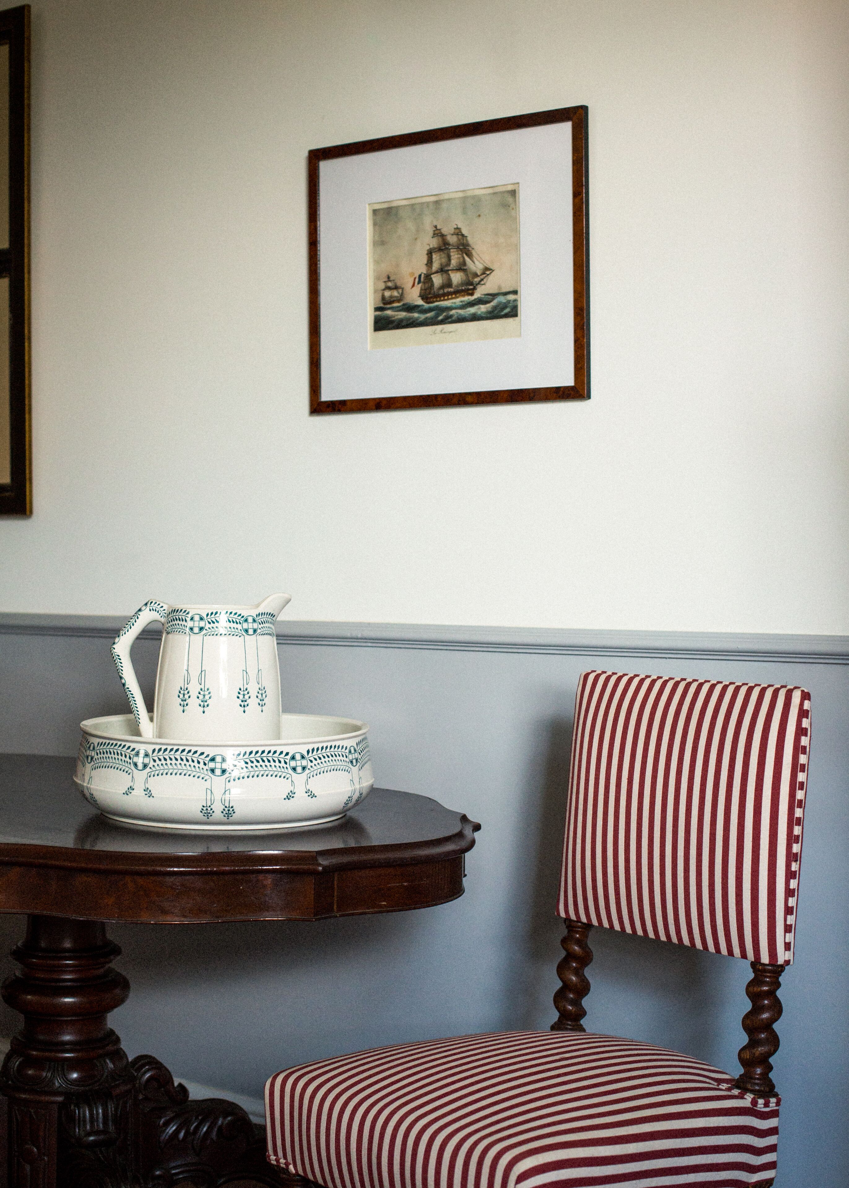 Un comedor con una mesa de madera, una silla a rayas y un cuadro en la pared.