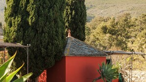 A poolside area with lounge chairs, a red building, and a stone wall.
