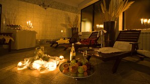 A dimly lit lounge area with a table set for a meal, a bottle of wine, and a fruit bowl. - Hotel Villa Letan (Vodnjan)