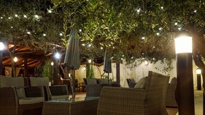 An outdoor seating area with wicker furniture and string lights. - Hotel Villa Letan (Vodnjan)