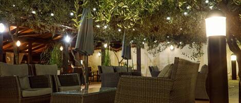 An outdoor seating area with wicker furniture and string lights.