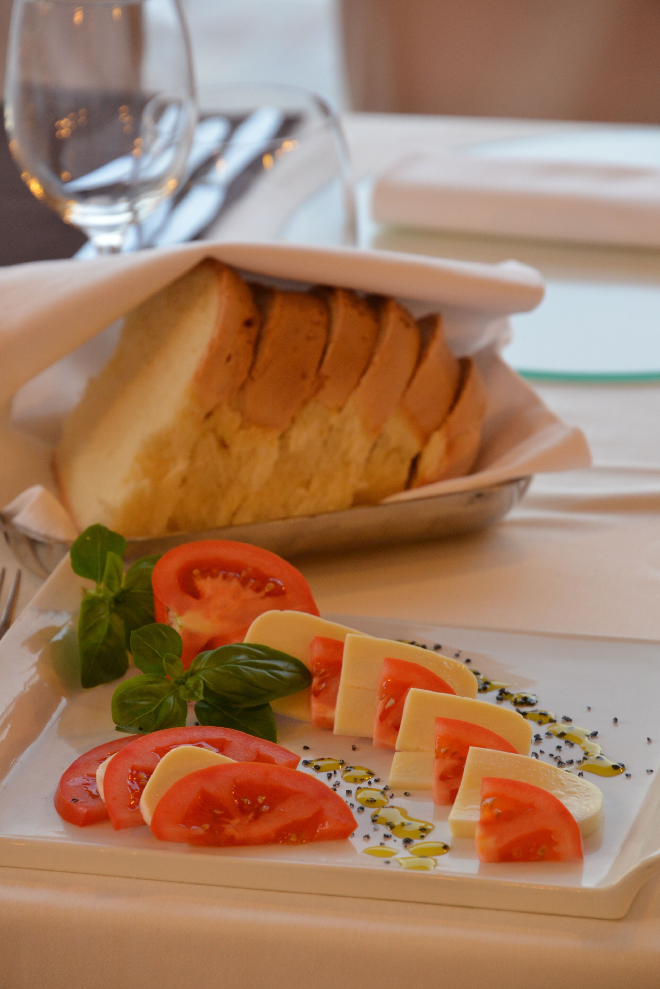 Um prato com rodelas de tomate, manjericão e queijo.