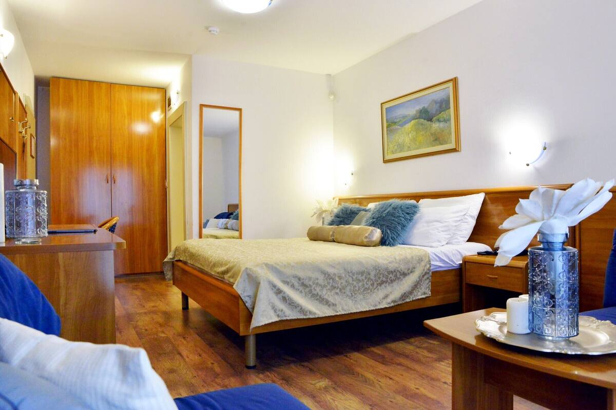 A bedroom with a bed, bedside table, lamp, and a painting on the wall.