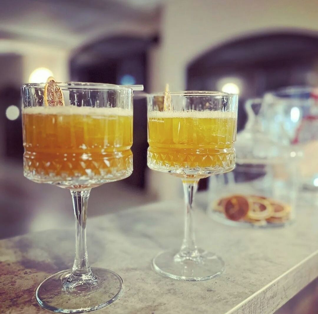 Two glasses of beer on a bar counter.