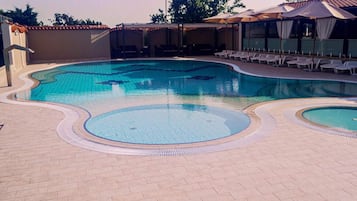 Una piscina al aire libre de temporada, sombrillas