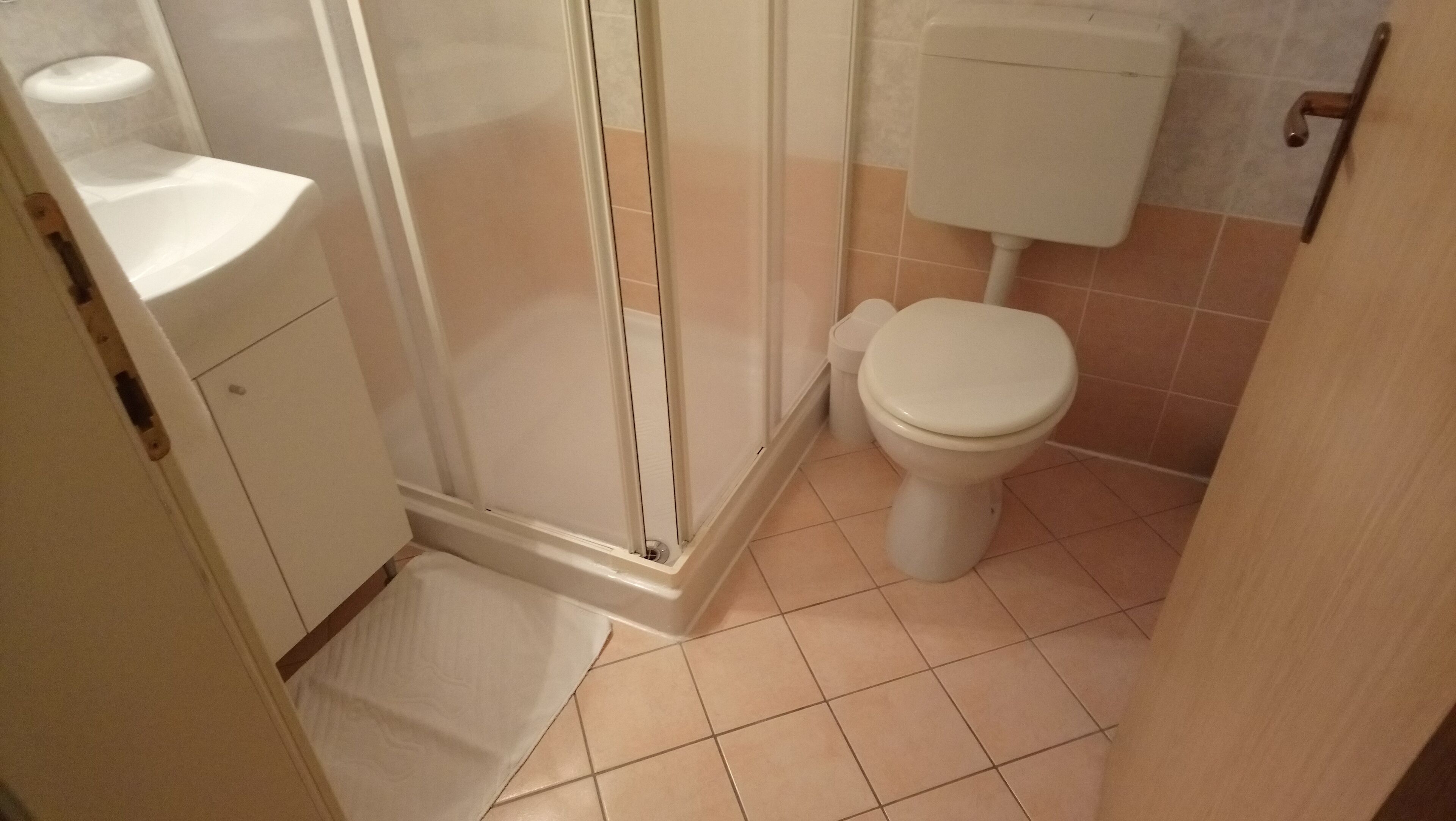 Un baño con inodoro, cabina de ducha y lavabo.
