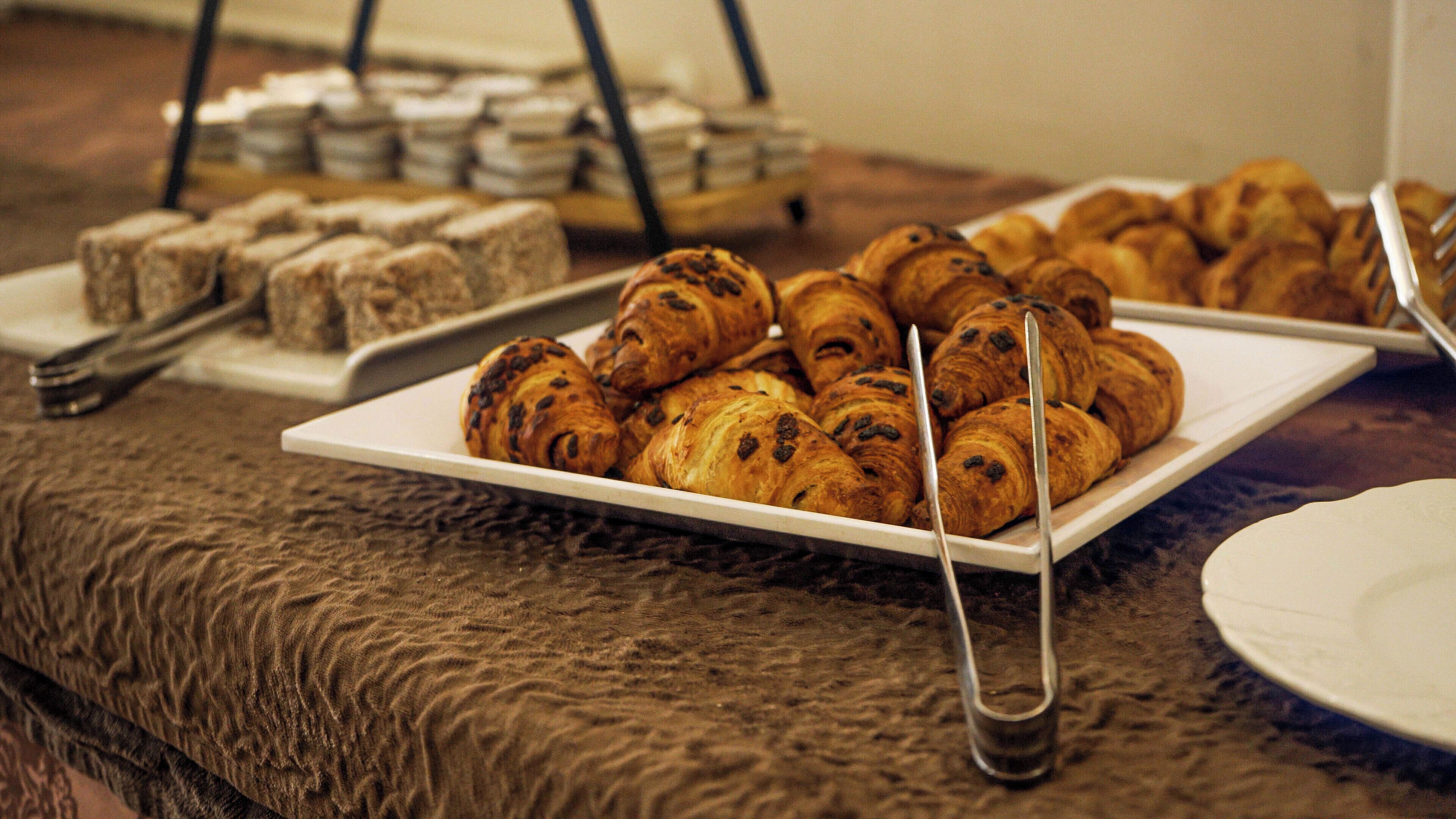 Une table de buffet avec des pâtisseries et un plateau de sandwichs.