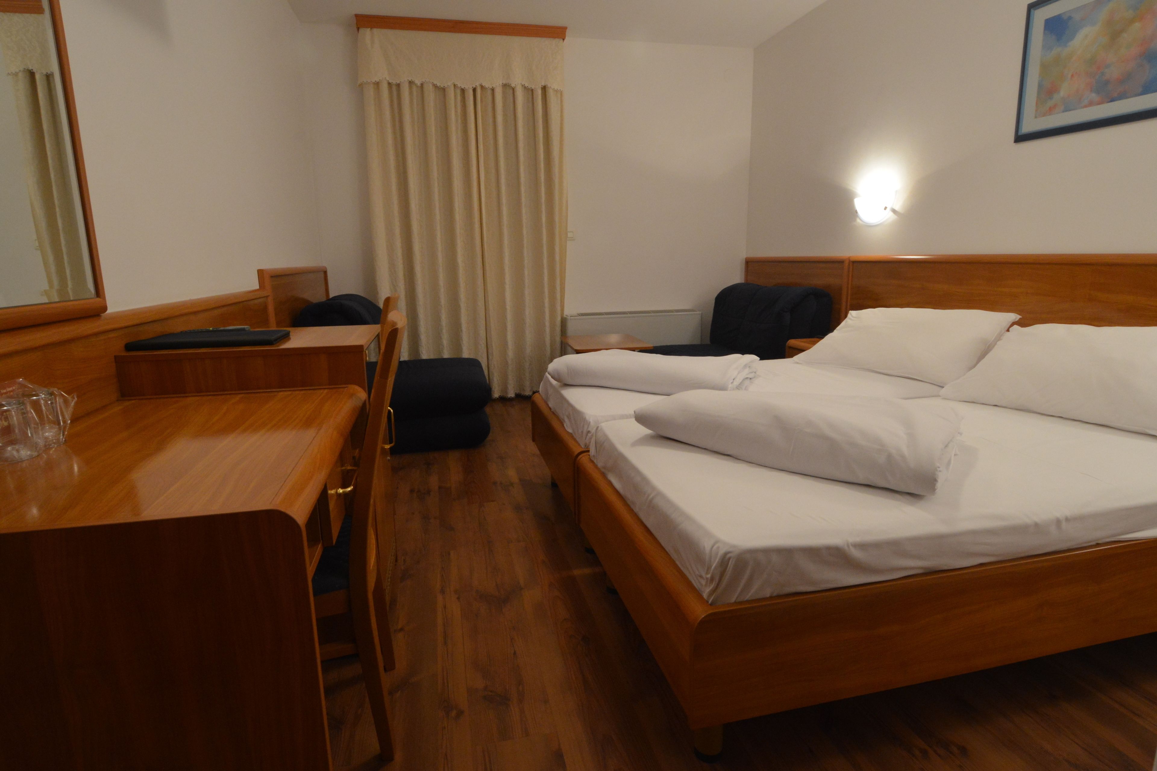 Hotelkamer met een houten bed, een bureau, een stoel en een raam met gordijnen.