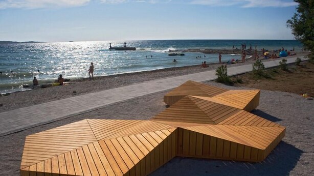 A beach with wooden seating areas and a paved walkway along the shore. - Hotel Villa Letan (Vodnjan)