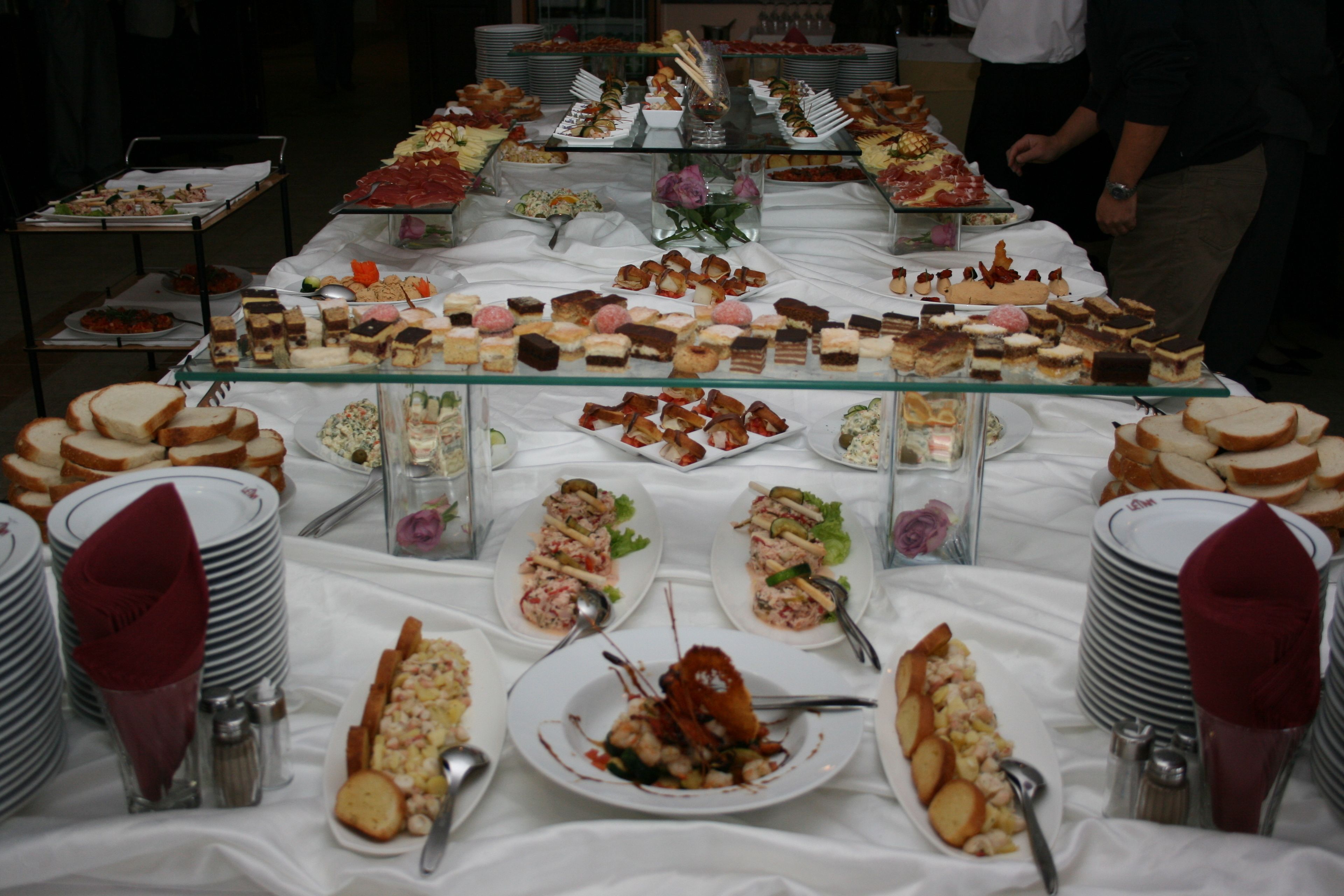 A buffet table with various food items and plates.