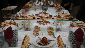 A buffet table with various food items and plates.