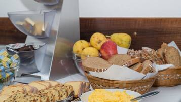Una mesa de buffet con diversos alimentos, incluyendo pan, huevos y frutas.