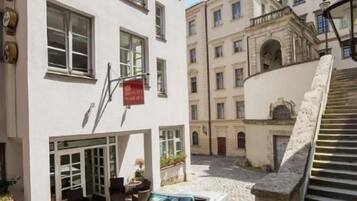 Ein Gebäude mit einem Kopfsteinpflasterhof, einem geparkten Cabriolet und einer Treppe, die zu einer oberen Ebene führt.