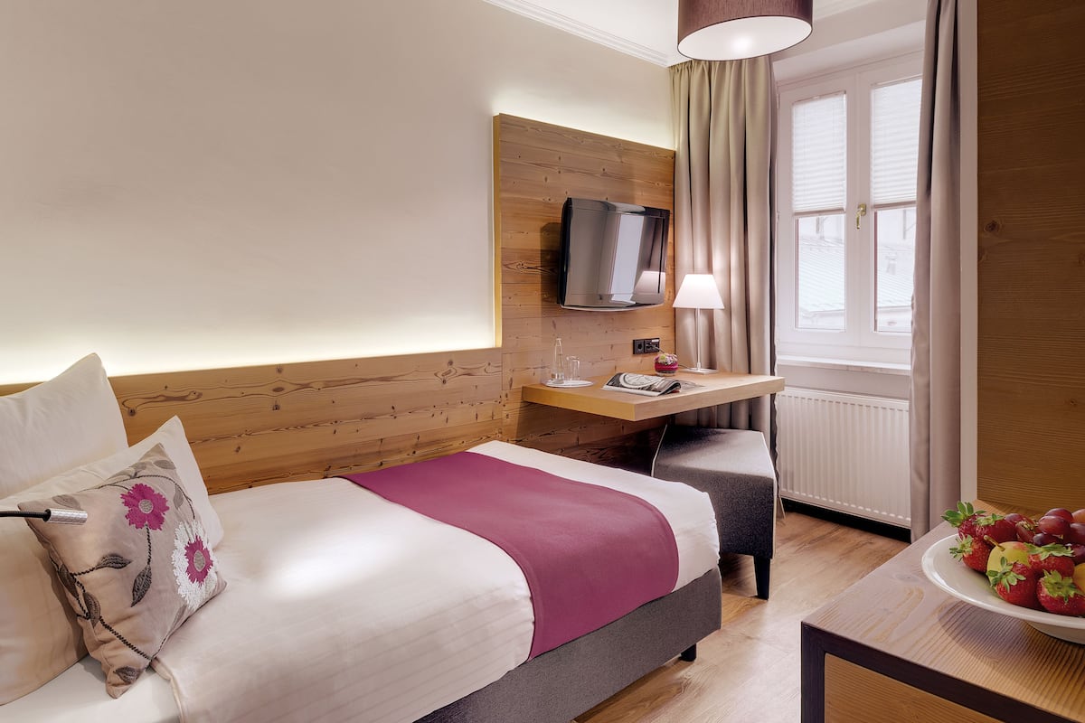 Habitación de hotel con cama, escritorio, televisor y un frutero.