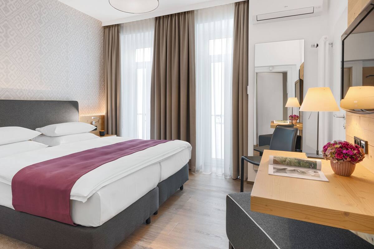 Una habitación de hotel moderna con una cama grande, un escritorio y un espejo.
