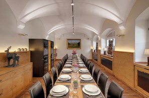 Mesa de jantar comprida posta para uma refeição em um espaço com teto em arco e lambris de madeira.