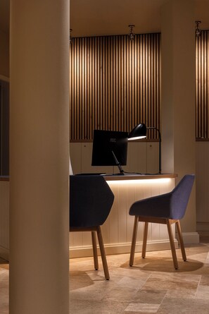 A modern kitchen with a built-in stove, a black AOC monitor, and two blue chairs. - LOEV - VELA Hotel (Binz)