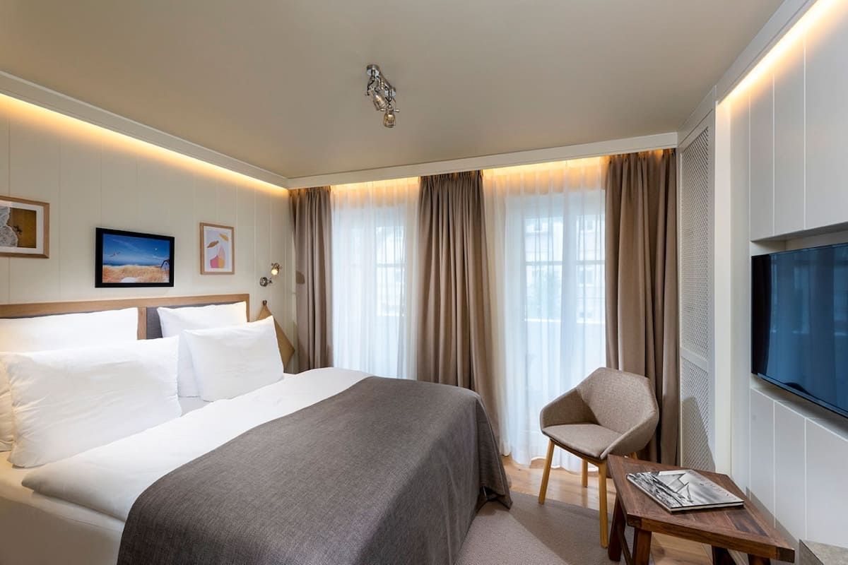 Habitación de hotel con una cama grande, una silla, un televisor y una mesita.