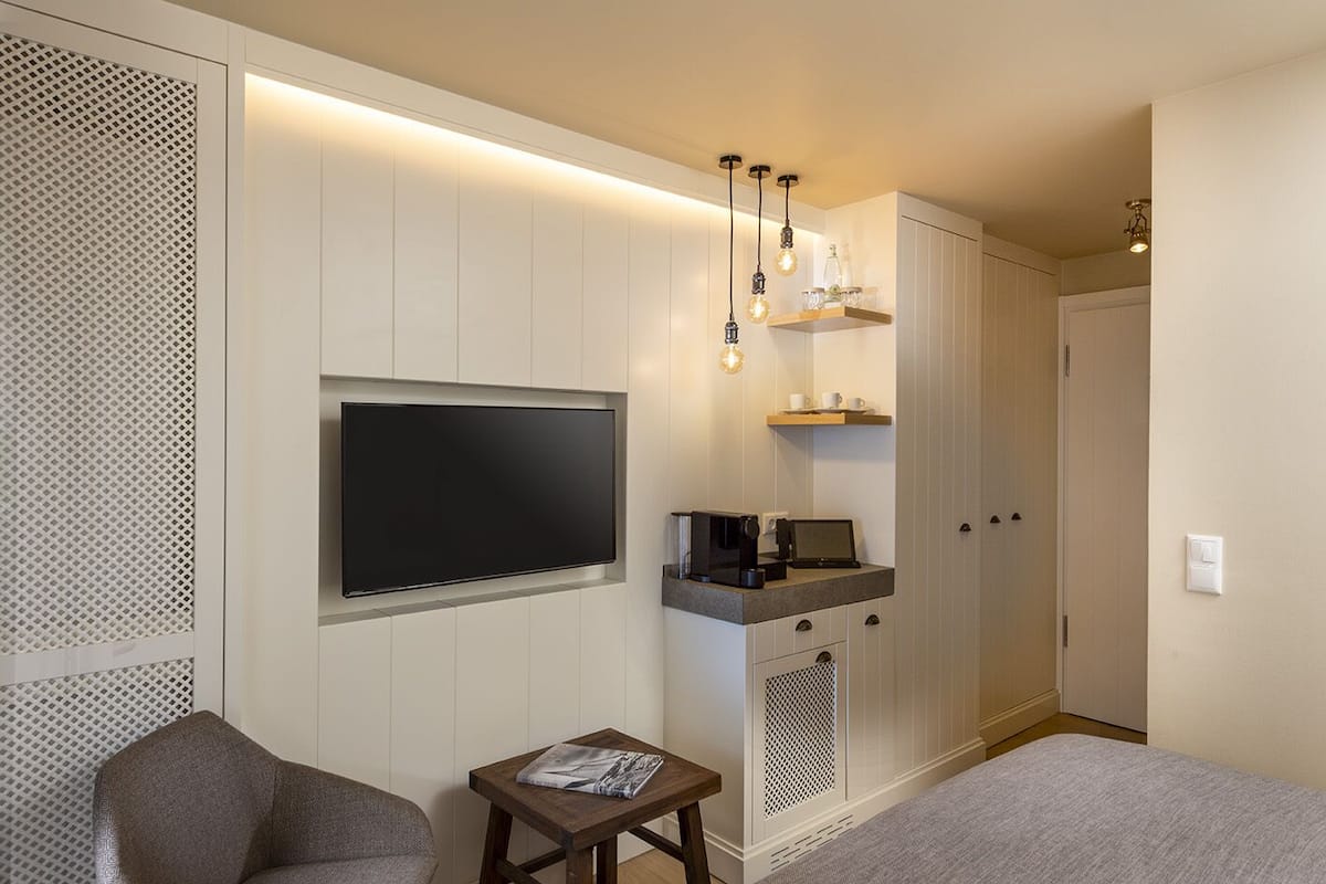 Un dormitorio moderno con una televisión de pantalla plana, una mesita con una revista, una cafetera y una cama.