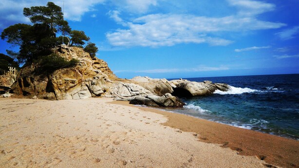 A beach with rocky cliffs and a clear sky. - Hotel GHT Xaloc (Castell-Platja d'Aro)