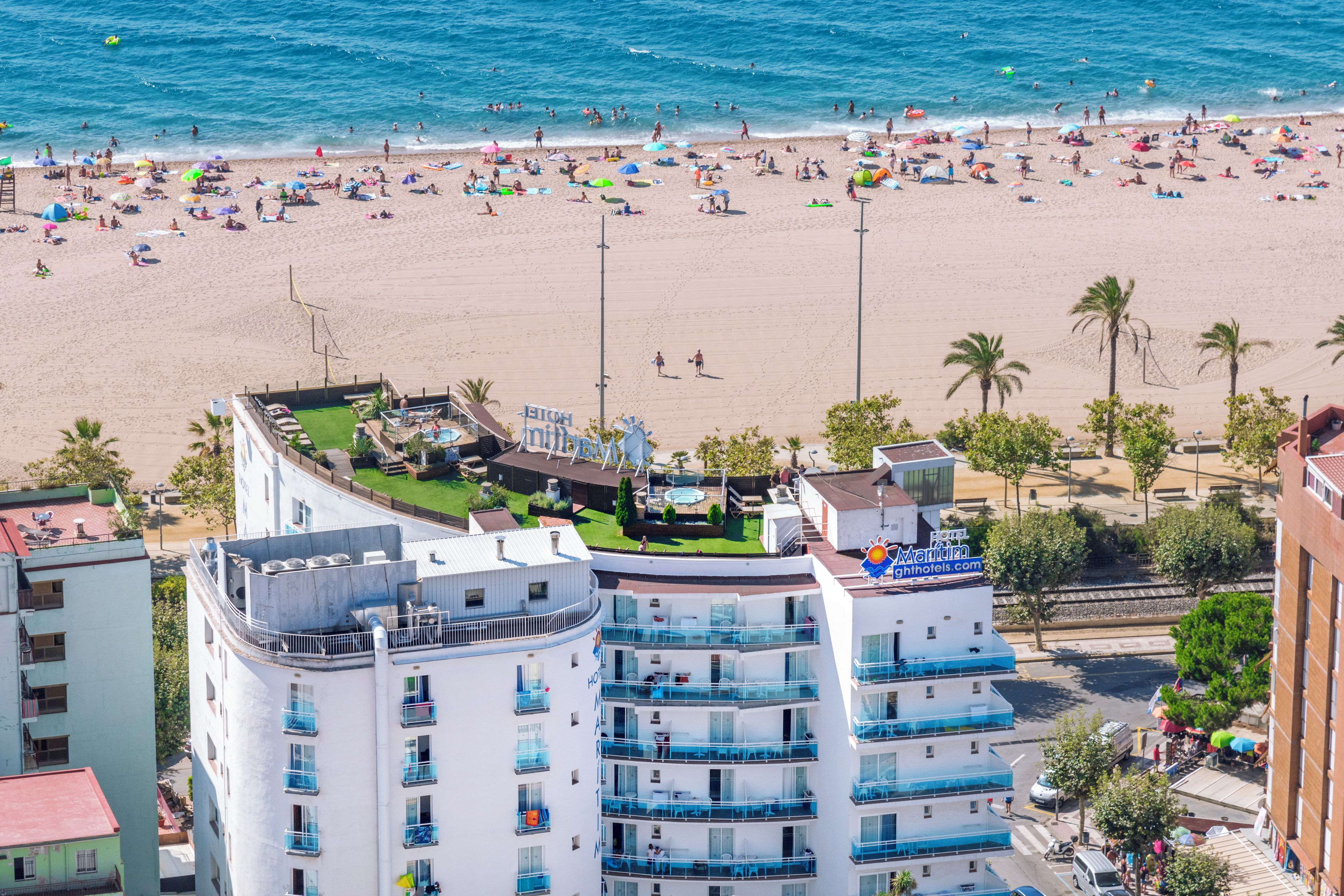 A hotel with multiple floors, balconies, and a rooftop pool area.