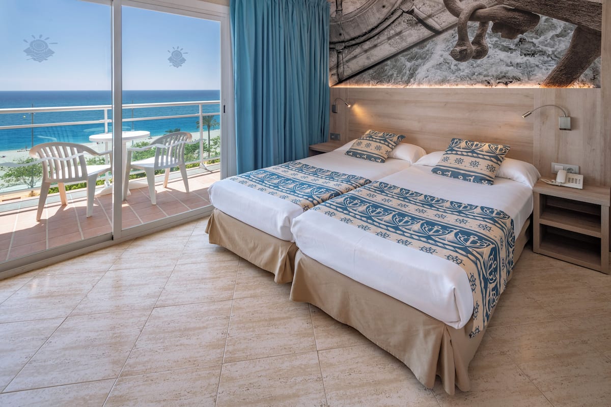 A bedroom with a large bed, a nightstand, and a view of the ocean.
