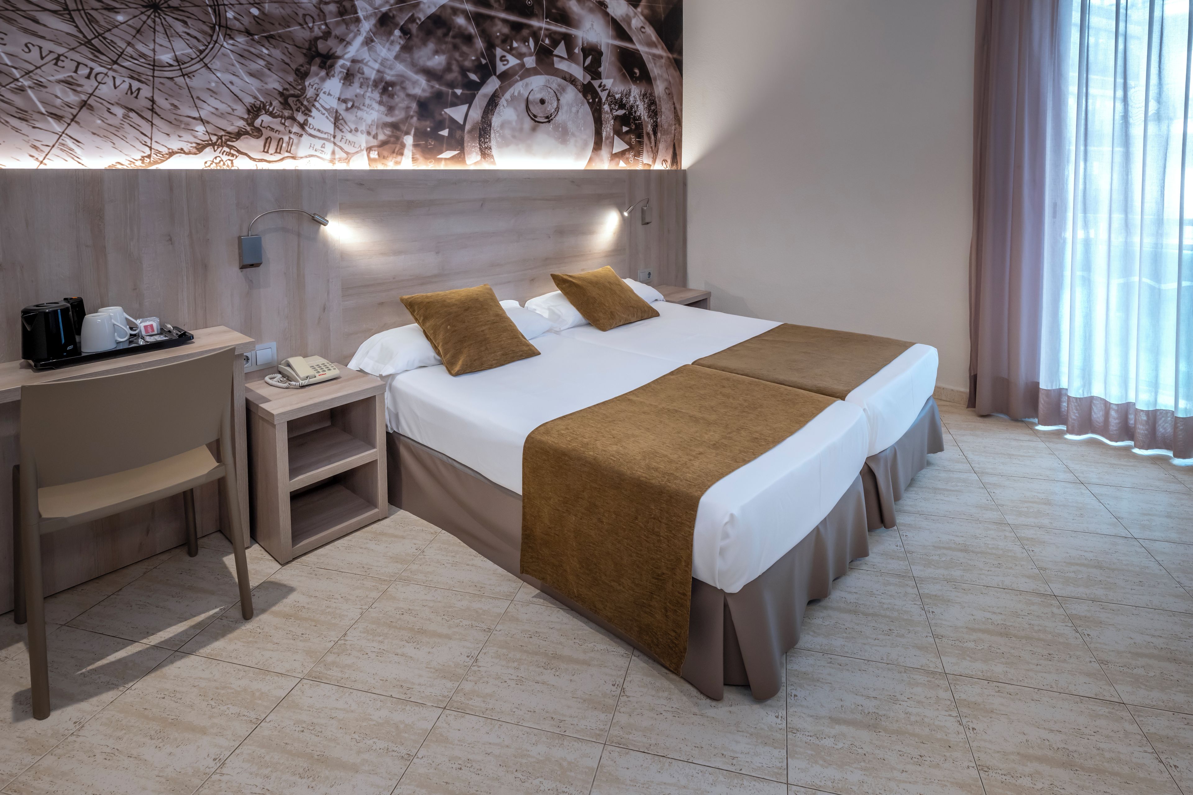 Quarto de hotel com cama, mesas de cabeceira, escrivaninha e mapa fixado na parede.