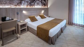 Quarto de hotel com cama, mesas de cabeceira, escrivaninha e mapa fixado na parede.