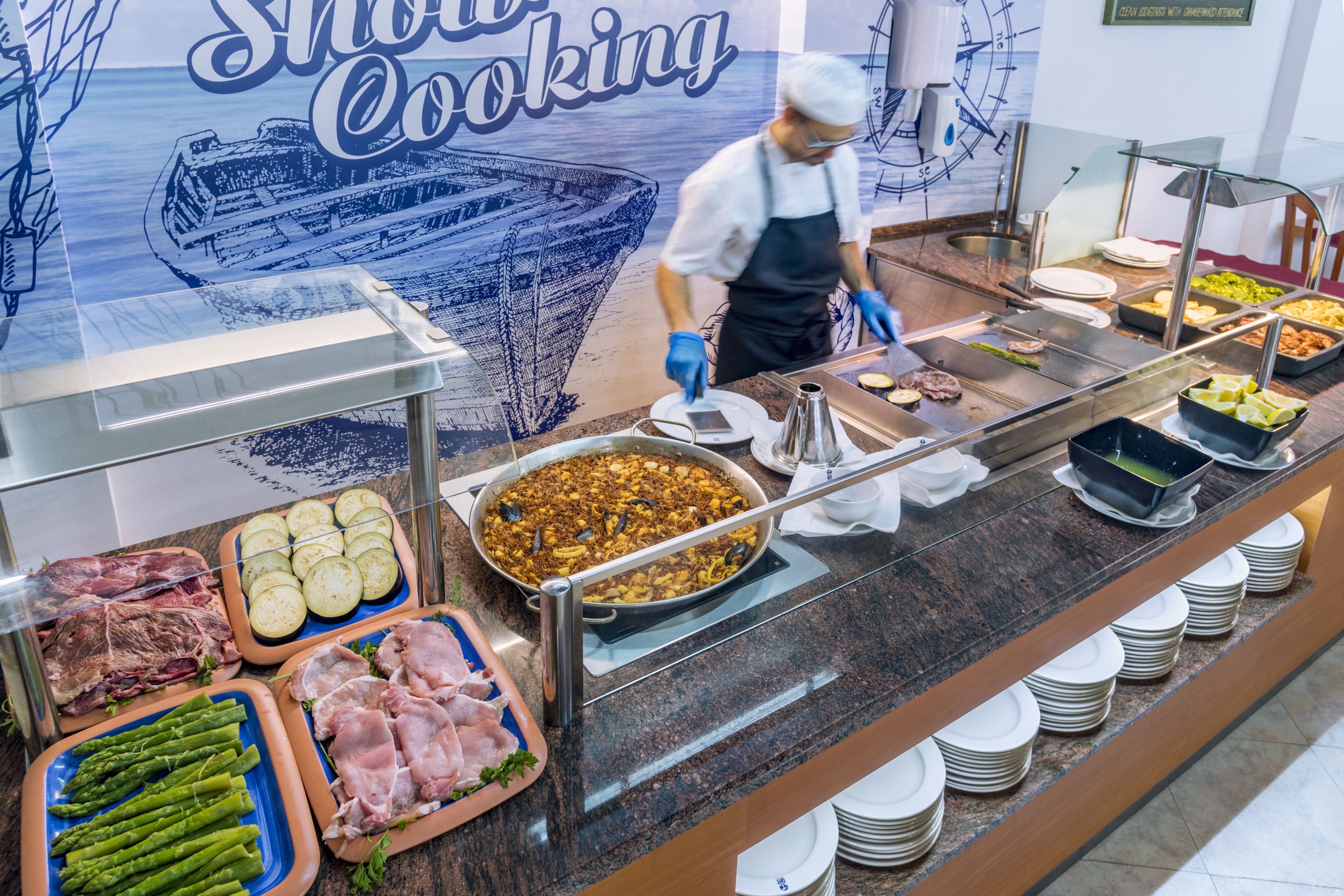 A buffet with various food items, including meats, vegetables, and a large pan of food.