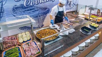 Un bufé con diferentes opciones de comida, incluyendo carnes, verduras y una gran bandeja de alimentos.