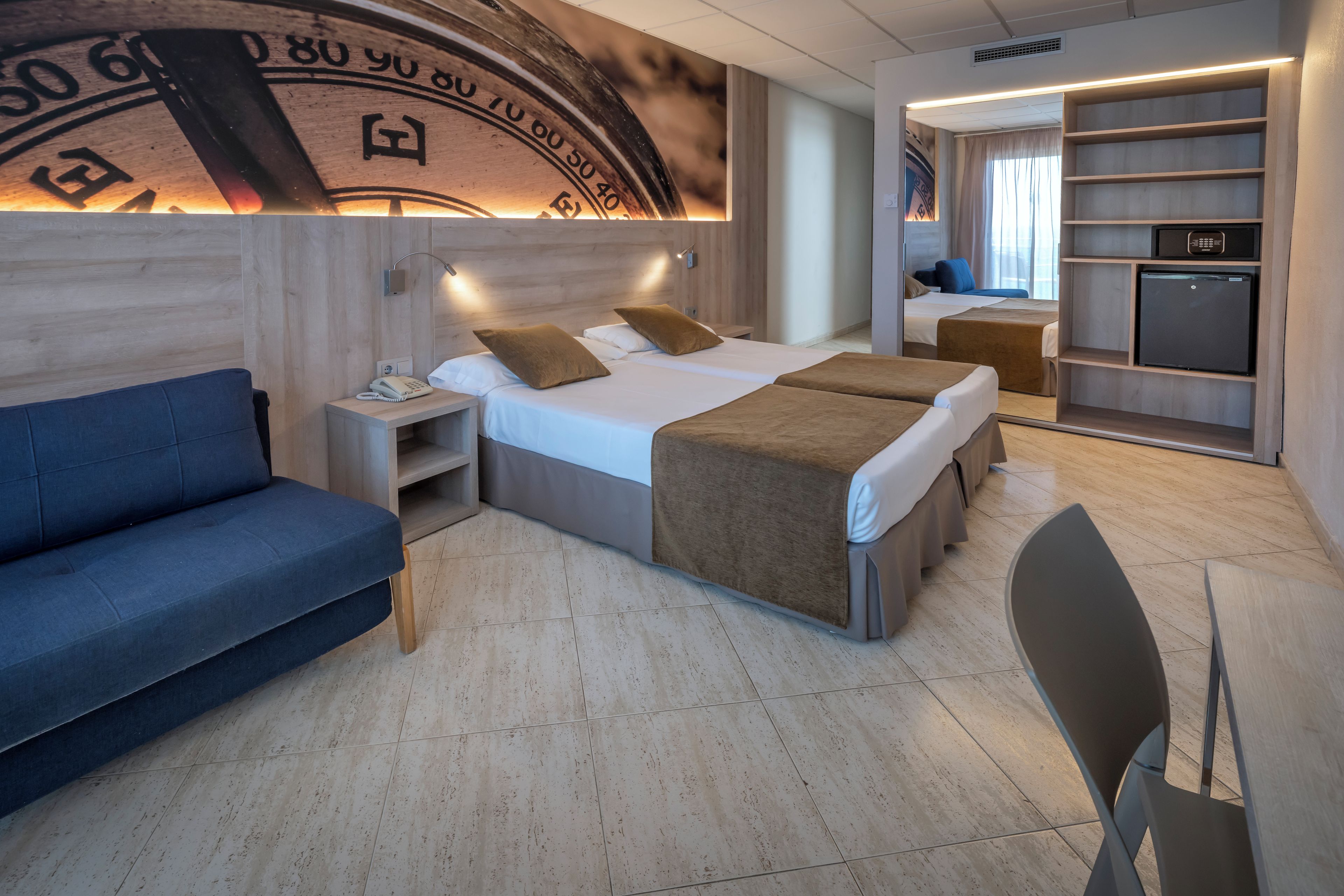 Ein modernes Hotelzimmer mit Bett, Sofa, Schreibtisch und Minibar.