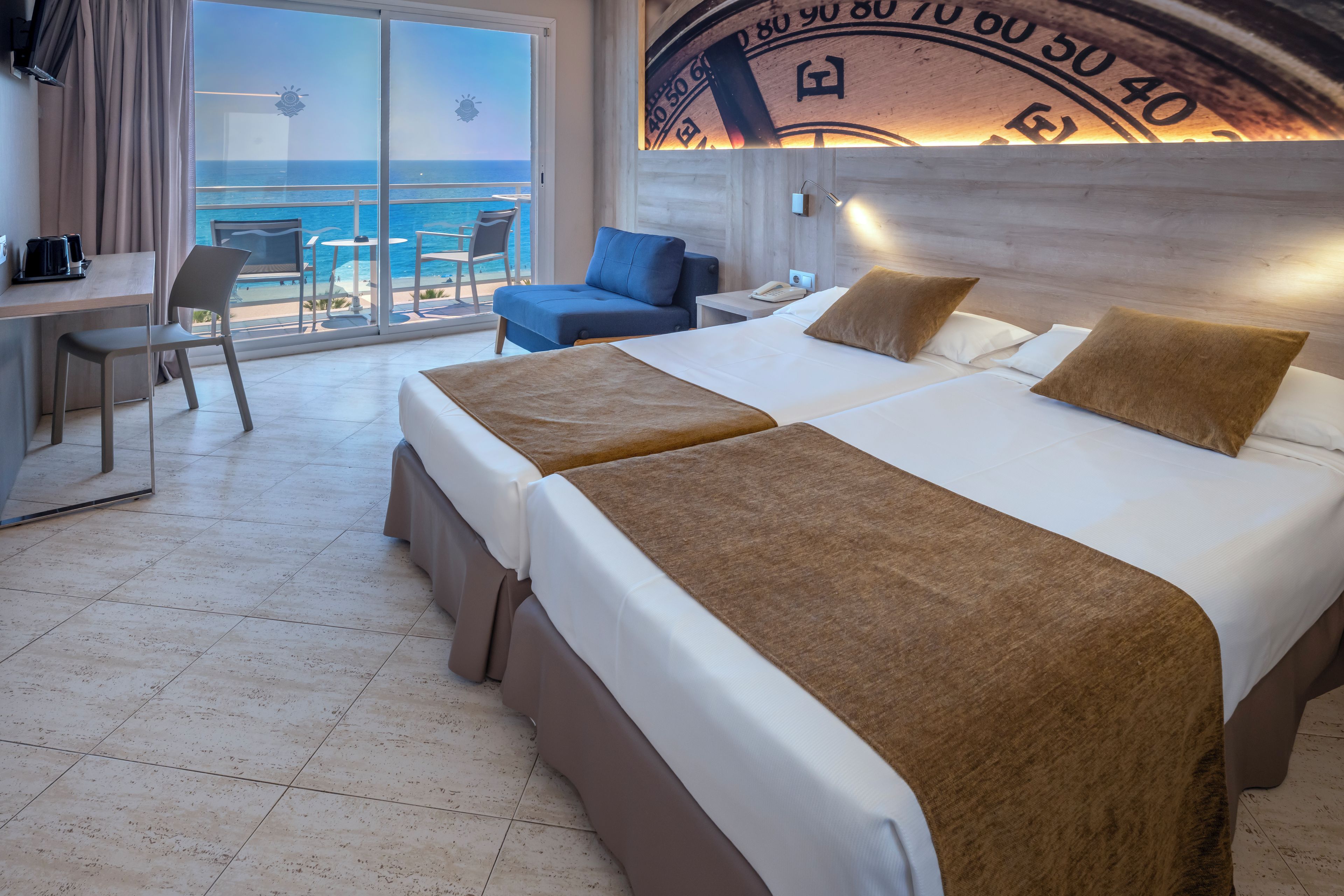 Ein Hotelzimmer mit zwei Betten, einem Schreibtisch und Meerblick.