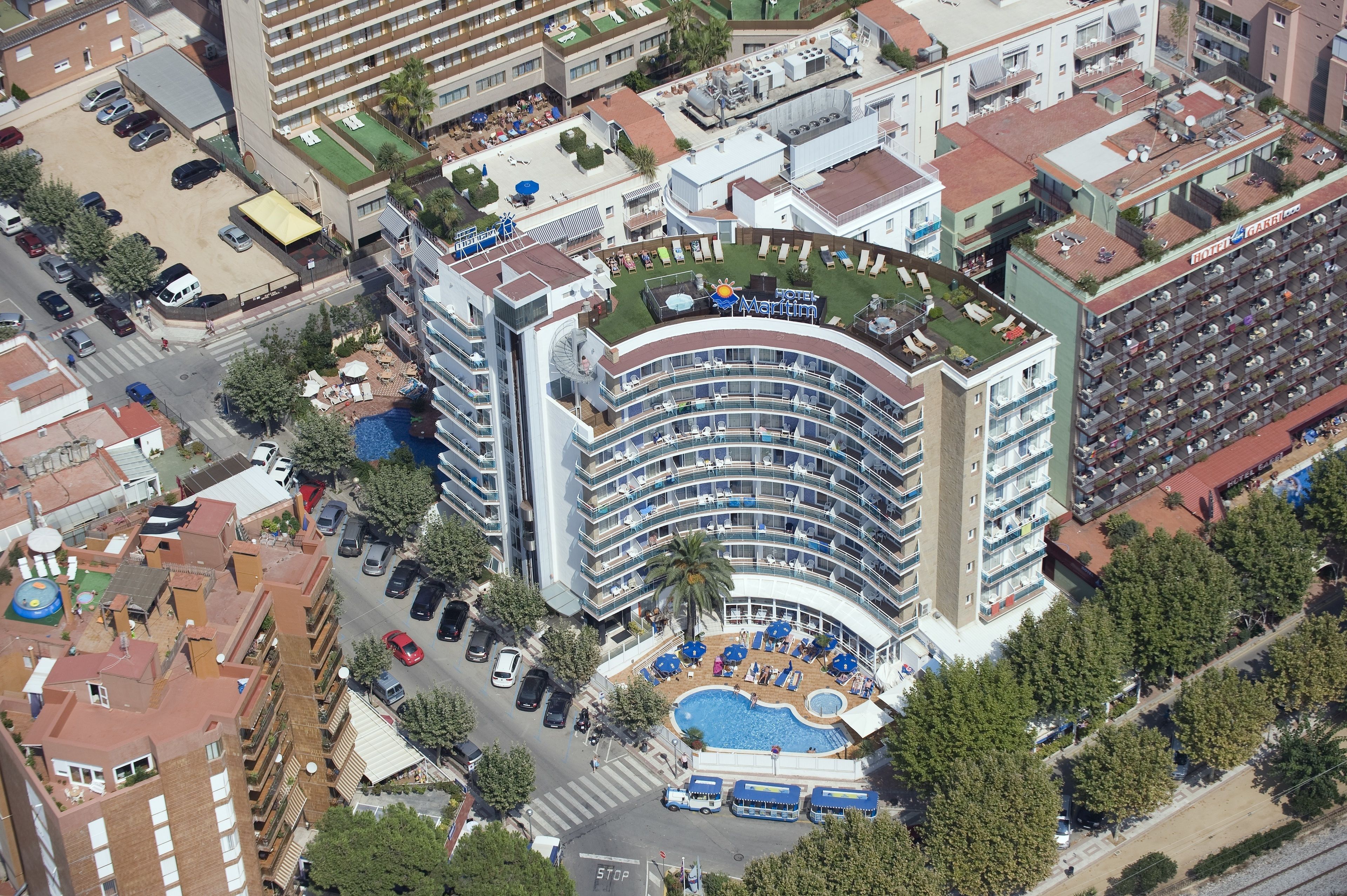 A multi-story hotel with a curved facade, a rooftop pool, and a landscaped courtyard.