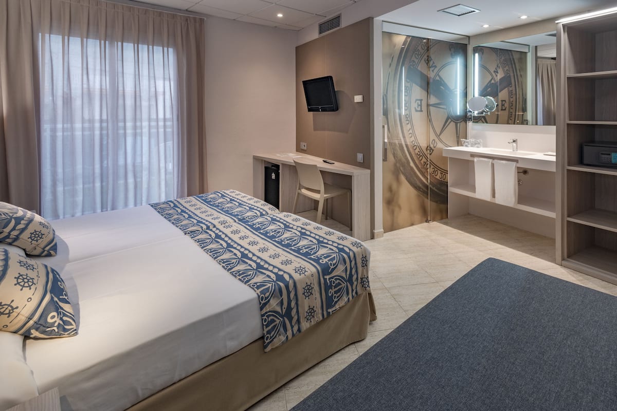 A hotel room with a bed, desk, and bathroom.