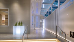 En modern hotellobby med en trappa, en receptionsdisk och en stor glasvägg.
