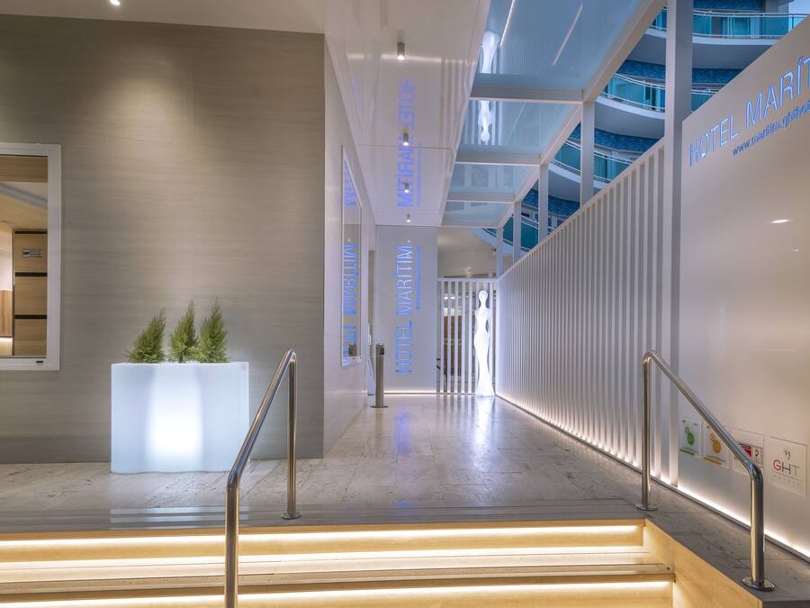A modern hotel lobby with a staircase, a reception desk, and a large glass wall.