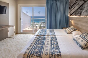 A hotel room with a bed, a TV, a balcony with a view of the sea, and a wooden headboard.