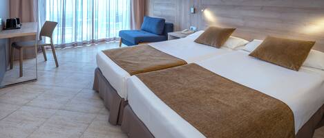 A hotel room with two beds, a desk, a chair, and a large window with curtains.