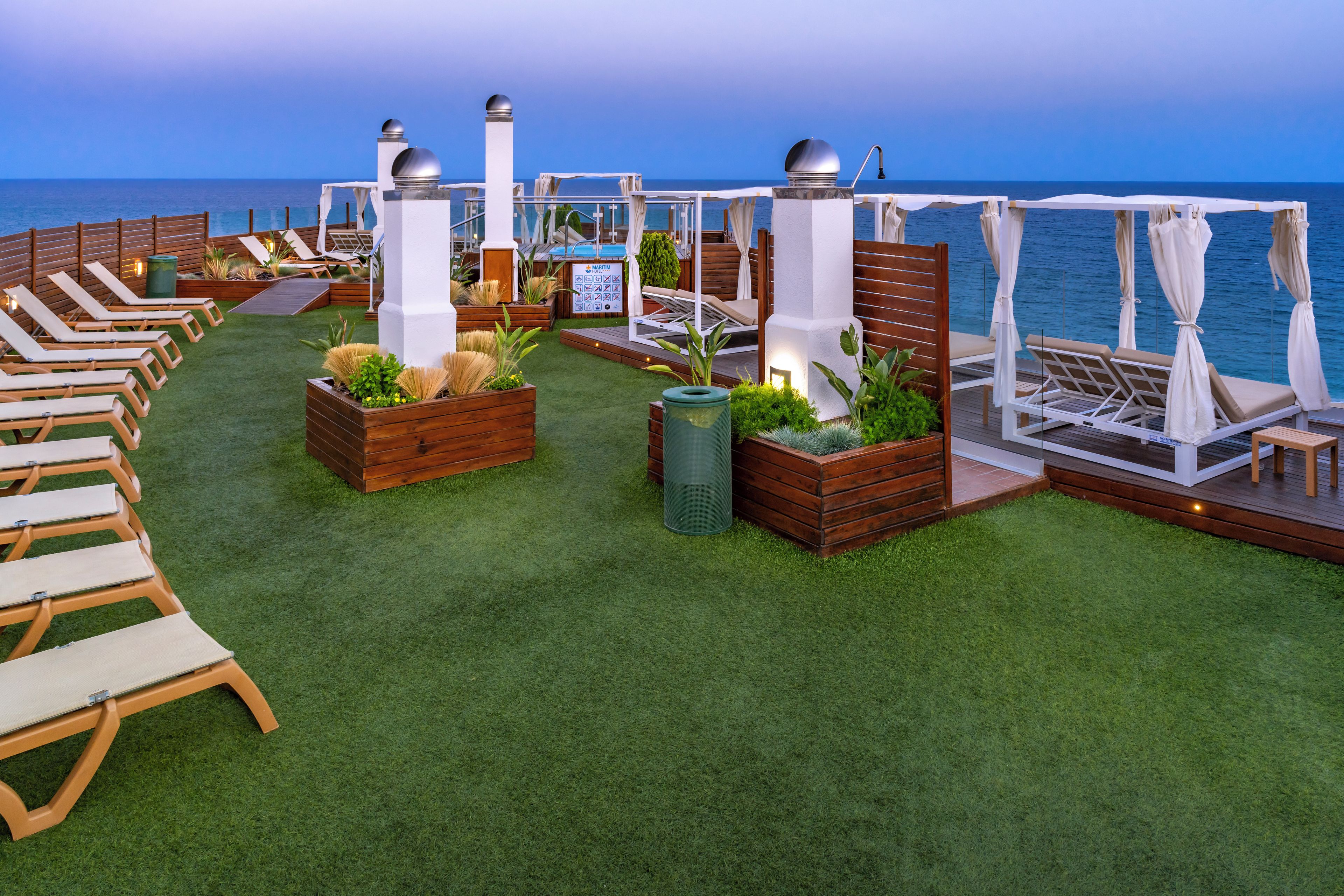 A deck with lounge chairs and planters, overlooking the sea.