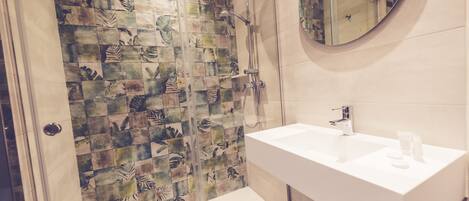 Un baño con ducha, lavamanos y espejo.